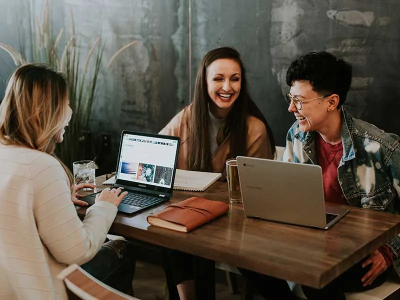 contact Women gathering at a table with laptops